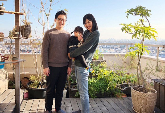 バルコニーに立っているご夫婦とお子様