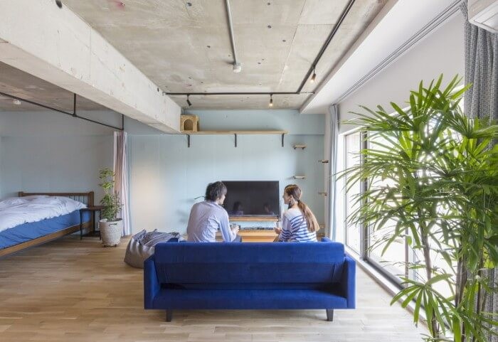 リビングルームと青いソファに腰掛けるご夫婦の後ろ姿