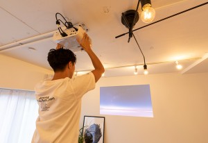 ホームプロジェクターを壁に投写するTさん